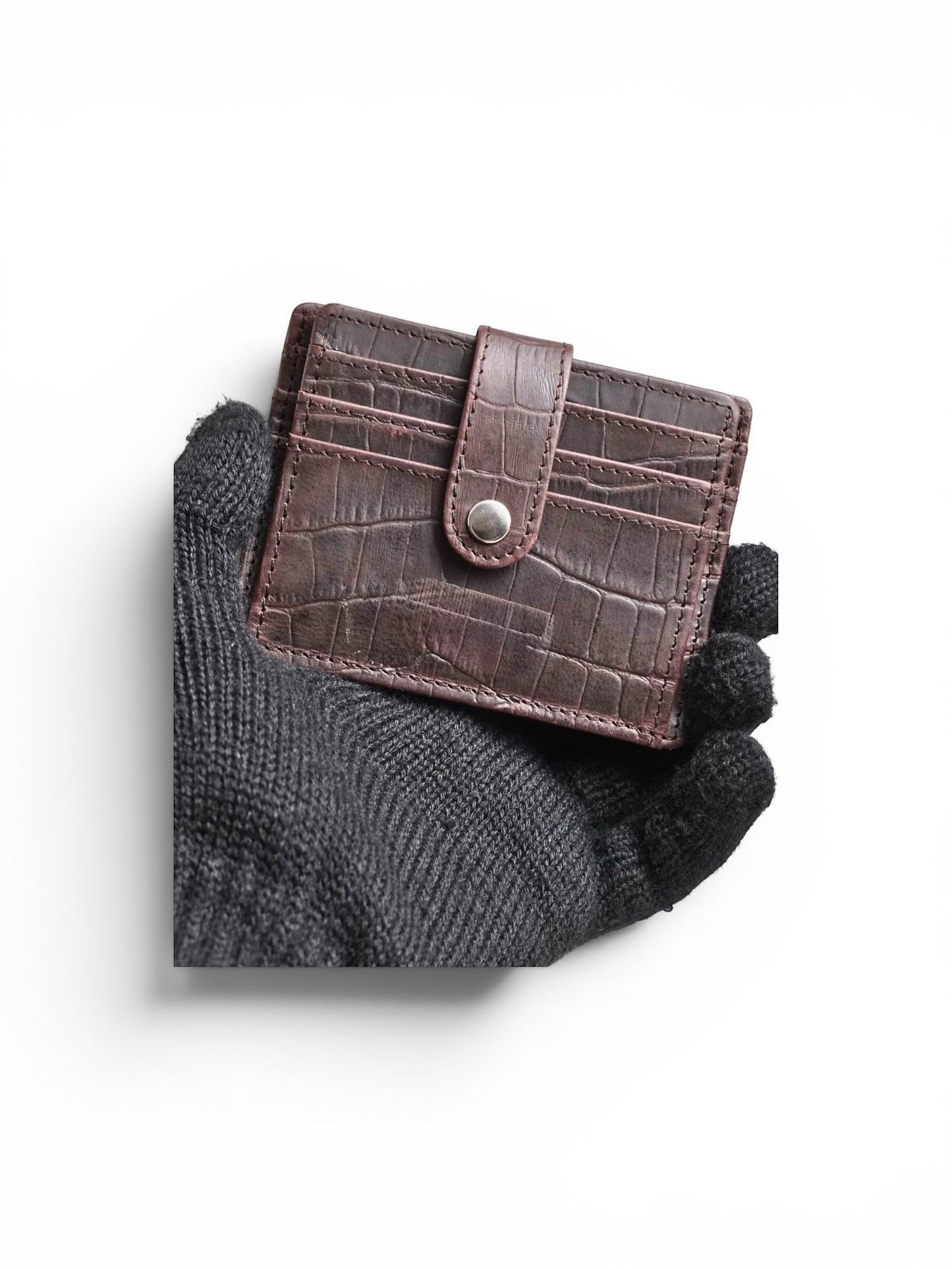 Seragino dark brown croc-texture leather card holder with snap closure and multiple card slots, held in a black gloved hand.